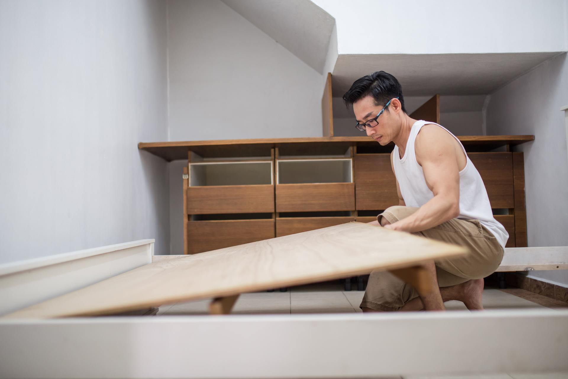 Un homme mûr asiatique installe des meubles.